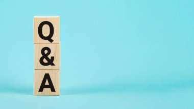 Tahta bloklardan soru-cevap kısaltması, harflerle, sorularla ve soru-cevap kavramlarıyla. Sorular ve cevaplar konsepti. Mavi zemin üzerinde alfabe Q ve A olan tahta blok küp