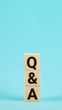 Tahta bloklardan soru-cevap kısaltması, harflerle, sorularla ve soru-cevap kavramlarıyla. Sorular ve cevaplar konsepti. Mavi zemin üzerinde alfabe Q ve A olan tahta blok küp