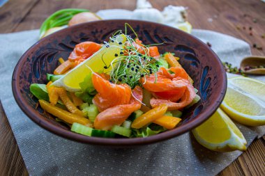 Füme somon, avokado ve ballı hardal soslu vişneli domates salatası. Tahta masadaki sağlıklı salata. Üst görünüm