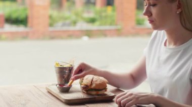 hamburger and garnish in the form of french fries. Take one piece of french fries with your fingers and dip in tomato ketchup sauce. Healthy food without trans fats.