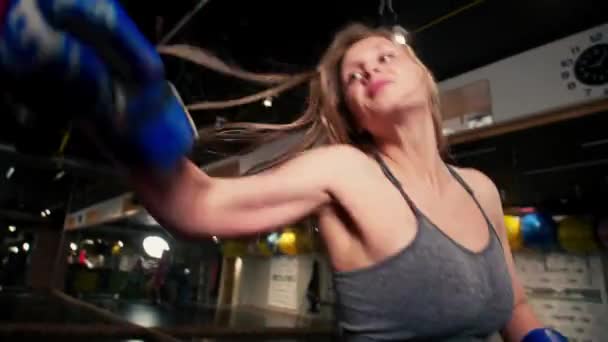 女戦士はパンチを訓練しスローモーションでパンチバッグを打ち負かしボクシングジムでのトレーニング日強さフィットボディ — ストック動画