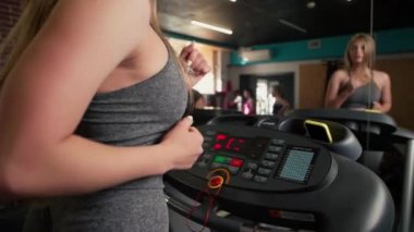 Spor salonunda koşu bandında koşan fitness kadını. Sporcu spor salonunda çalışan bir makine kullanır. Güzel kız spor kulübünde kardiyo antrenmanı yapıyor. 120fps