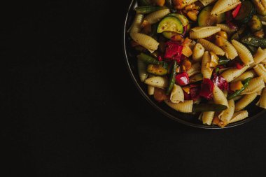 Sebzeli sebze salatası ve siyah arka planda baharatlar.