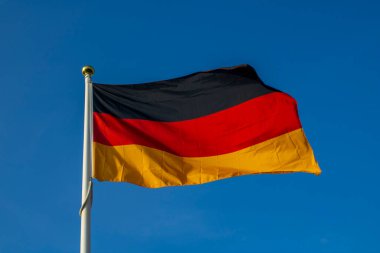 Arkasında açık mavi bir gökyüzü olan Alman bayrağı..