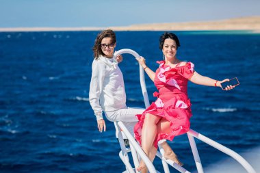 Güneşli bir yaz gününde yatın burnunda dinlenen iki kadın.