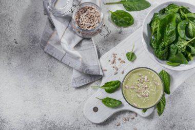 Bir bardak taze ıspanak, ayçiçeği ve açık arkaplanda susam tohumlu ev yapımı sağlıklı yeşil smoothie. Yiyecek ve içecek, diyet ve sağlıklı beslenme konsepti