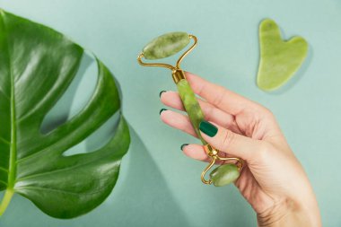 Yeşil taştan iki kafası olan ve yüzüne masaj yapan bir kadın el.