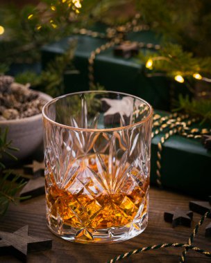Bir bardak viski ya da koyu arkaplanda noel süsü olan bir burbon. Yeni yıl, Noel ve kış bayramı Viski ruh hali konsepti