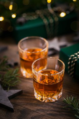 Ahşap arka planda tatil süslemesi olan iki kadeh viski ya da burbon. Yeni yıl, Noel ve kış bayramı Viski ruh hali konsepti