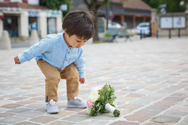 Lindo niño jugando al aire libre con un ramo de flores — Foto de Stock