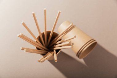 Tek kullanımlık kağıt sofra takımı. Bej arka planda fincanlar ve pipetler. Plastiksiz ve sıfır atık kavramı.