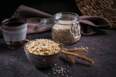Koyu ahşap arka planda buğday kulaklı kabuklu arpa taneleri. Sağlıklı ve diyet gıda konsepti.