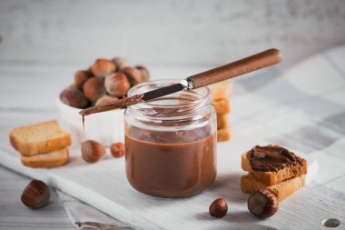 Beyaz ahşap arka planda kahvaltıda fındıklı çikolatalı tost.