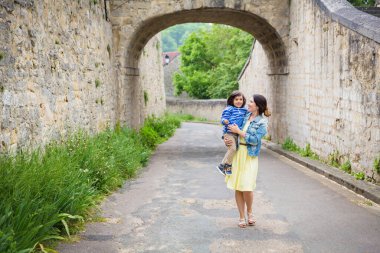 Anne ve küçük doğulu yakışıklı erkek bebek eski kasabada dışarıda oynuyorlar..