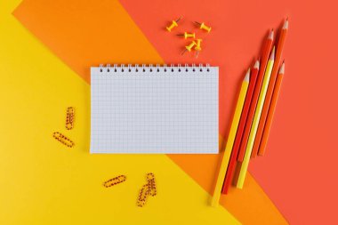 Sarı ve turuncu ofis masası boş defter ve diğer ofis malzemeleriyle dolu. Kopyalama alanı olan üst görünüm, düz yatay.