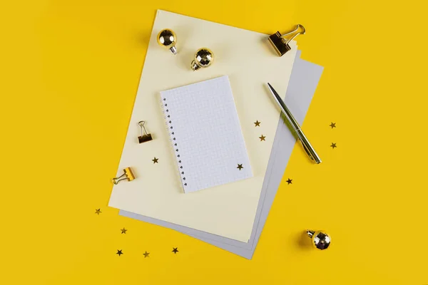 New year decoration of yellow office desk table with blank notebook and other office supplies. Top view with copy space, flat lay.