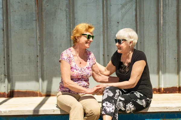 Two smiling elderly women are happy to meet each other, sit, talk and laugh together. Senior women are happy to communicate