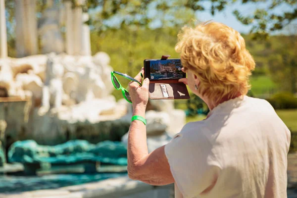 Пожилая Женщина Фотографирует Мобильный Телефон Красивый Фонтан Парке — стоковое фото