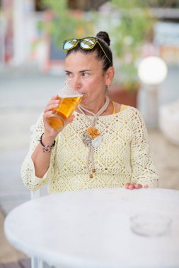 Plaj kafesinde bira içen ve yaz gününün tadını çıkaran güzel genç bir kadının portresi.