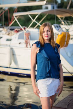 Güneşli bir yaz gününde marinada poz veren çekici bir kadın ve mutlu tatillerin tadını çıkarıyor.