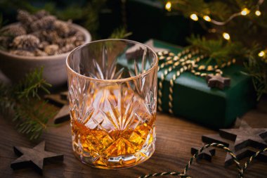 Bir bardak viski ya da koyu arkaplanda noel süsü olan bir burbon. Yeni yıl, Noel ve kış bayramı Viski ruh hali konsepti
