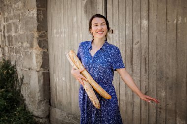 Young pretty woman standing with french baguettes in her hands in the countryside