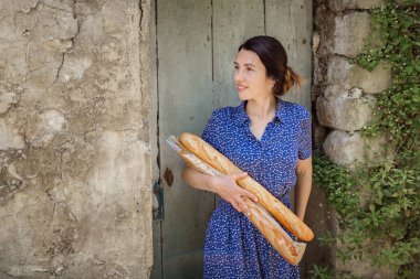 Young pretty woman standing with french baguettes in her hands in the countryside