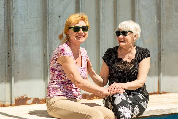 Two smiling elderly women are happy to meet each other, sit, talk and laugh together. Senior women are happy to communicate