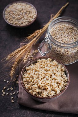 Koyu ahşap arka planda buğday kulaklı kabuklu arpa taneleri. Sağlıklı ve diyet gıda konsepti.