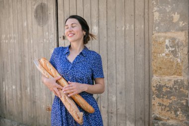 Young pretty woman standing with french baguettes in her hands in the countryside