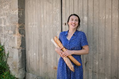 Young pretty woman standing with french baguettes in her hands in the countryside