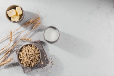 Bir kase soyulmuş arpa tanecikli lapa ve hafif arka planda buğday. Sağlıklı ve diyet gıda konsepti.