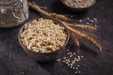 Koyu ahşap arka planda buğday kulaklı kabuklu arpa taneleri. Sağlıklı ve diyet gıda konsepti.