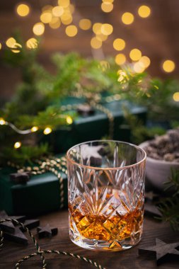 Bir bardak viski ya da koyu arkaplanda noel süsü olan bir burbon. Yeni yıl, Noel ve kış bayramı Viski ruh hali konsepti