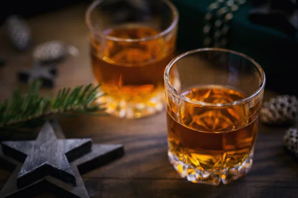 Whiskey, brandy or liquor shot and Christmas decorations on wooden background. Winter holidays concept.