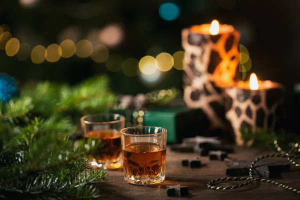 Whiskey, brandy or liquor shot and Christmas decorations on wooden background. Christmas holidays mood concept.