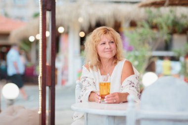 Portrait of a young woman drinking beer on the terrace of a beach cafe on a summer sunny day