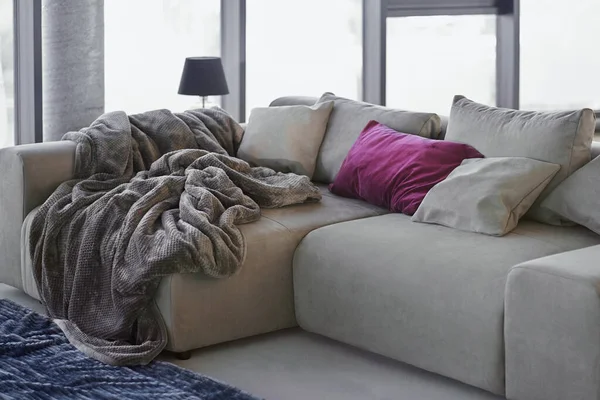 Cozy grey couch with soft blanket and pillows at living room — Stock Photo, Image