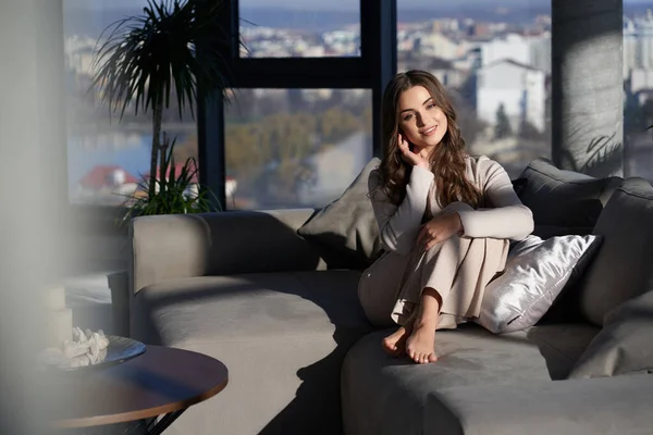 Çekici bir kadın çıplak ayakla koltukta oturuyor. 