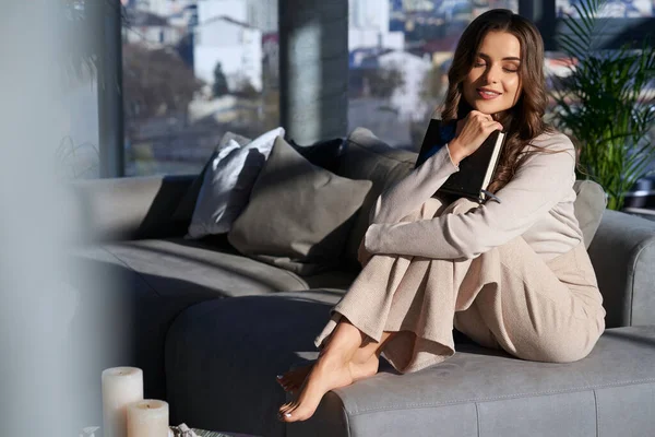 Kanepede elinde kitapla dinlenen bir kadın.