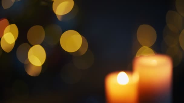 Velas ardiendo sobre fondo oscuro de luces navideñas — Vídeos de Stock