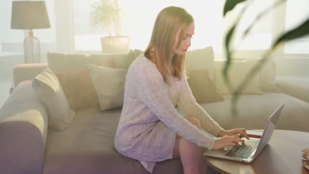 Aangename vrouw met behulp van laptop tijdens vrije tijd thuis — Stockvideo