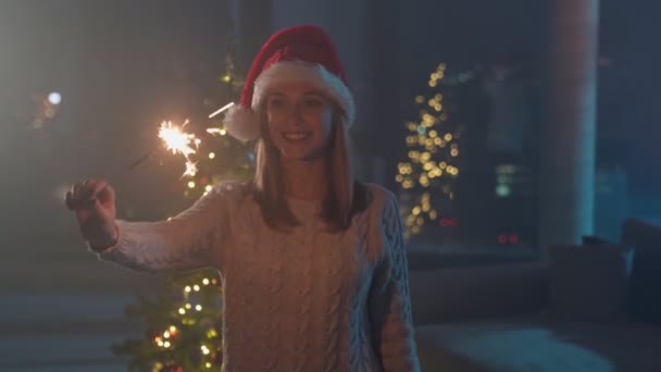 Mulher segurando faíscas enquanto estava perto da árvore de Natal — Vídeo de Stock