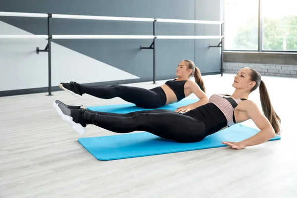 Naiset harjoittelevat vatsan lihaksia matot studiossa. — kuvapankkivalokuva