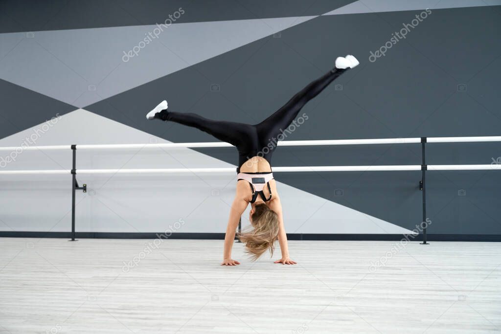 Woman doing wheel jump in dance hall.