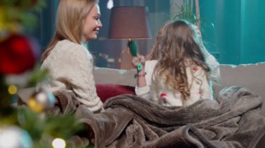 Anne, kış akşamını kanepede kızlarıyla geçiriyor.