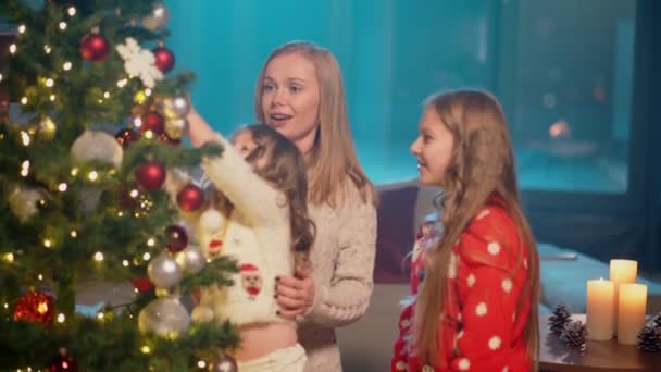 Dos niñas ayudando a la madre a decorar el árbol de Navidad — Vídeo de stock