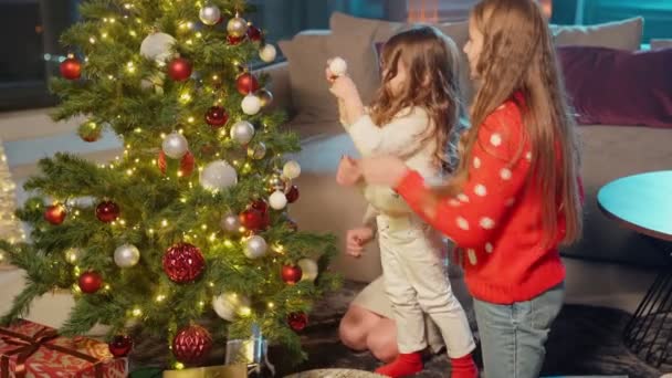 Evde Noel ağacı süsleyen kızları olan bir anne. — Stok video