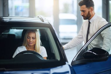 Satıcı, bayan alıcıya kuaförde yeni bir araba sunuyor.