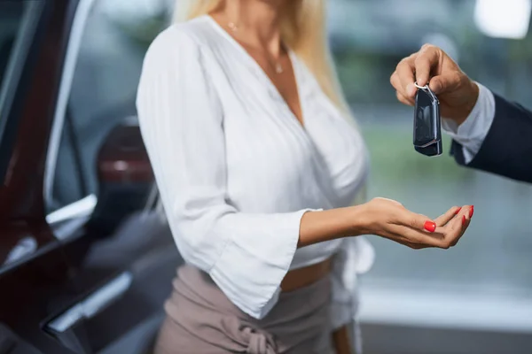 Close up de cliente feminino recebendo chaves do carro do vendedor — Fotografia de Stock